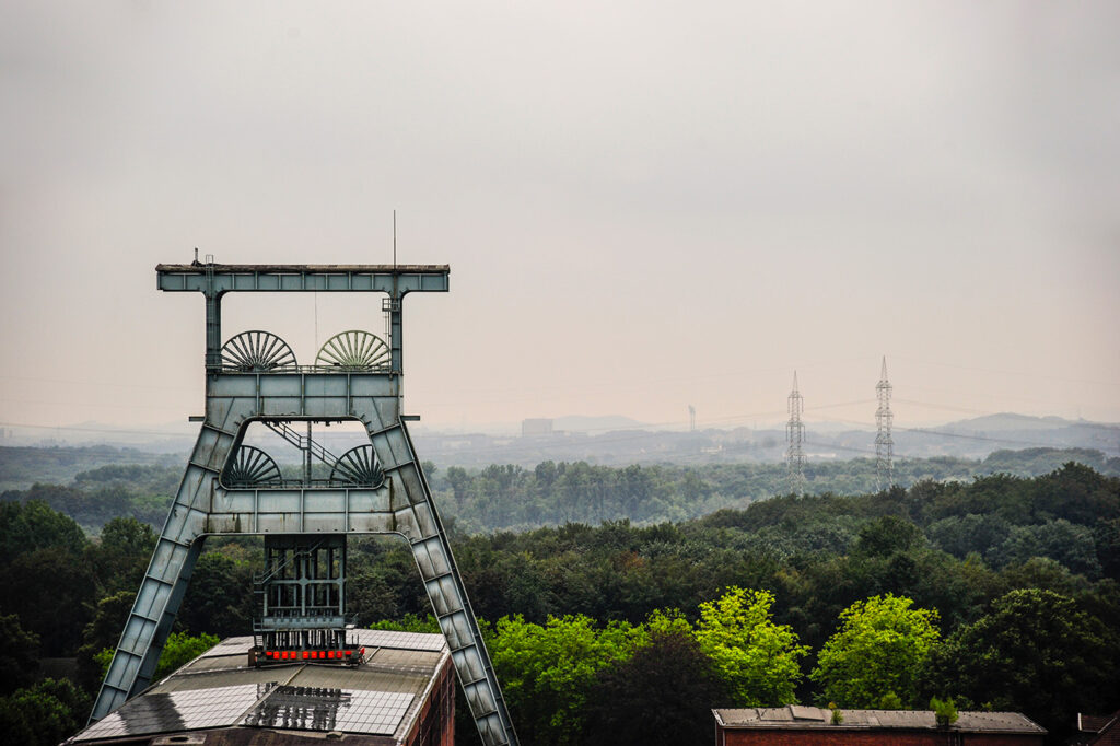 Diesiger Blick über das Ruhrgebiet. Im Vordergrund ein Doppelkopf-Fördergerüst. 