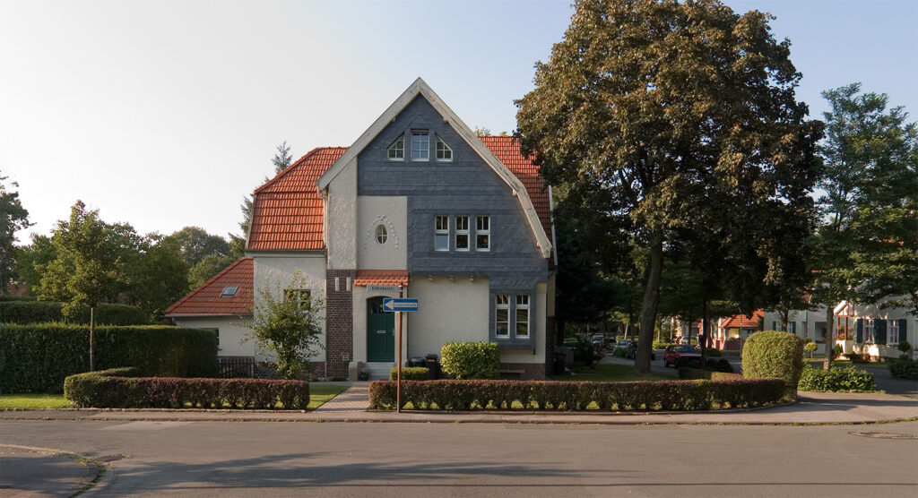 Ansicht eines Hauses mit Vorgarten und einem großen Erker mit Schieferfassade.